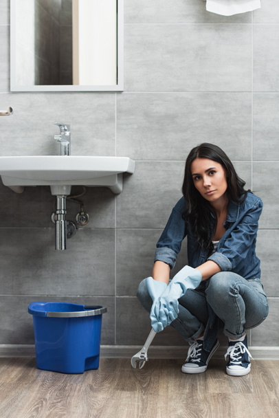 Tired girl with wrench sitting in bathroom - Photo, Image