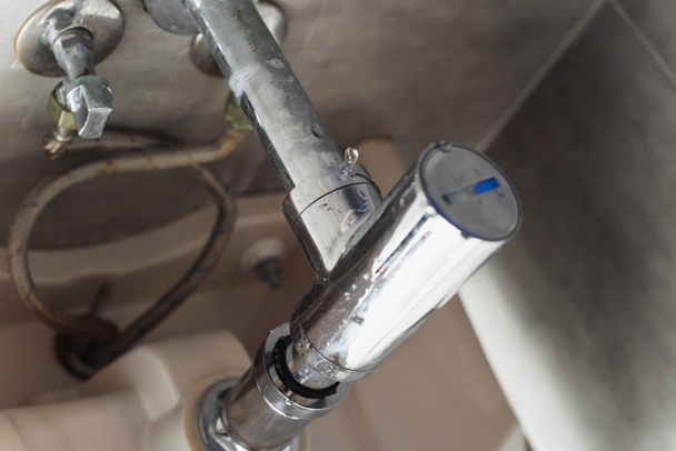 Damaged steel pipes under sink with water drops - Fotoğraf, Görsel