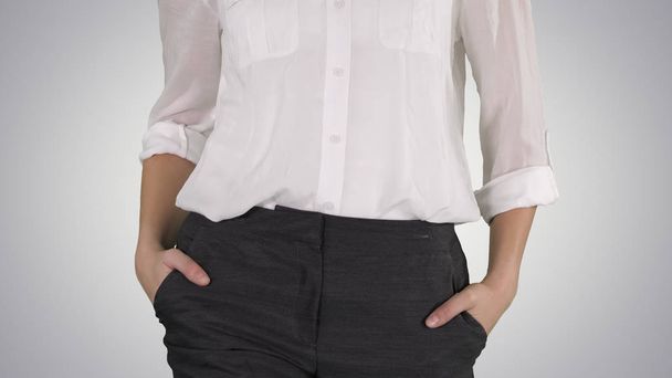 Relaxed business woman with walking with hands in her pockets on gradient background. - Foto, imagen