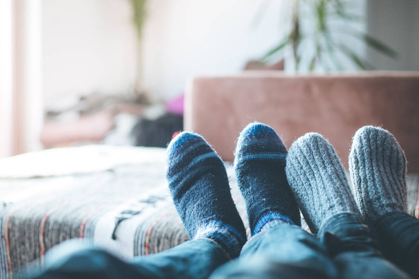 Feet with woollen socks in the wintertime: Couple is relaxing on the couch - Foto, Bild