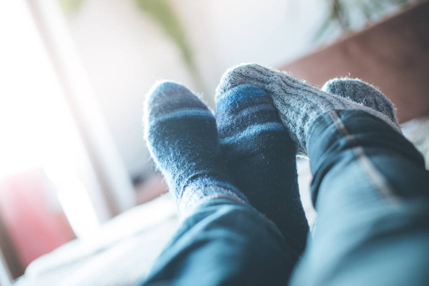 Feet with woollen socks in the wintertime: Couple is relaxing on the couch - Foto, Imagen