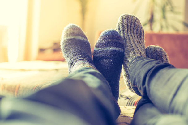 Feet with woollen socks in the wintertime: Couple is relaxing on the couch - Photo, Image