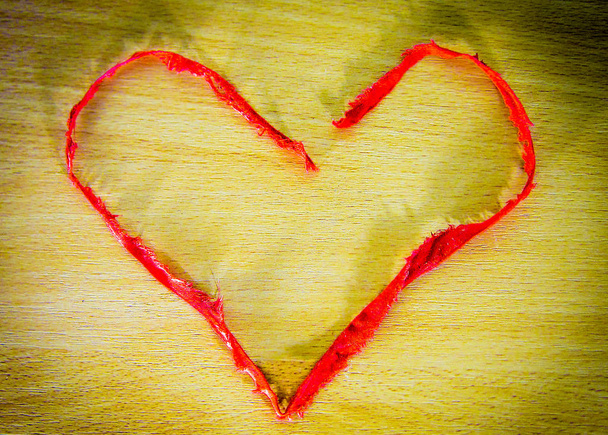 Bright red heart-1 from the band of fabric on a yellow brown wooden background. Suitable for the concept of romance, love, engagement, Valentine's Day, etc.  - Photo, Image