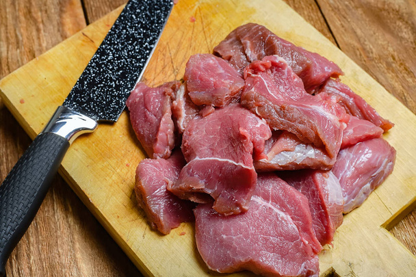 Raakaa lihaa puuleikkuulaudalla mustalla veitsellä. Lähikuva naudanlihaa kuiduilla. Näkymä ylhäältä
. - Valokuva, kuva