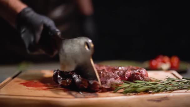 Male hand in black rubber gloves separates the pieces of meat lying on the cutting board with a cutting knife. Close up. Slow motion. - Felvétel, videó