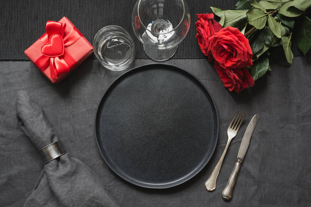 Valentine's day or birthday romantic dinner. Elegance table setting with red rose on black linen tablecloth. - Fotó, kép