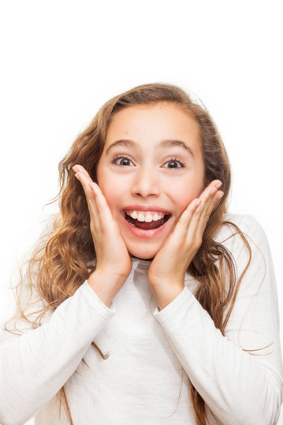 Smiling young girl looking happily surprised with hands on her chin isolated on white background - Photo, image