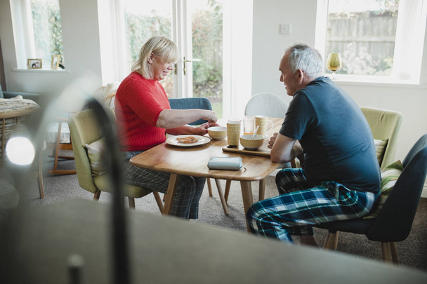 Mature couple are having breakfast together at the dining table in their home.  - 写真・画像