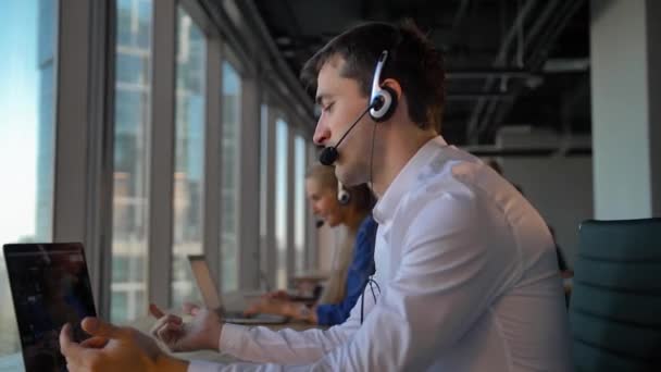 Όμορφος επιχειρηματία επιχειρηματία σε ακουστικό ζητώντας να cuctomers σε επιχειρηματικό γραφείο τηλεφωνικό κέντρο - Πλάνα, βίντεο