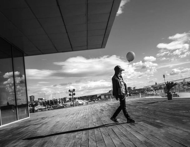 Валенсія, Іспанія - 5 листопада 2016. Хлопець у копиці стоїть біля будинку Велес - е - Вентс з зеленою кулькою в порту Валенсії (Іспанія).. - Фото, зображення