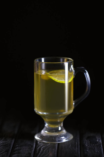 Low key photo of glass of lemon tea on wooden table - Foto, Imagen