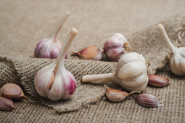 Bulbs and cloves of natural organic garlic on a linen mat - Fotó, kép