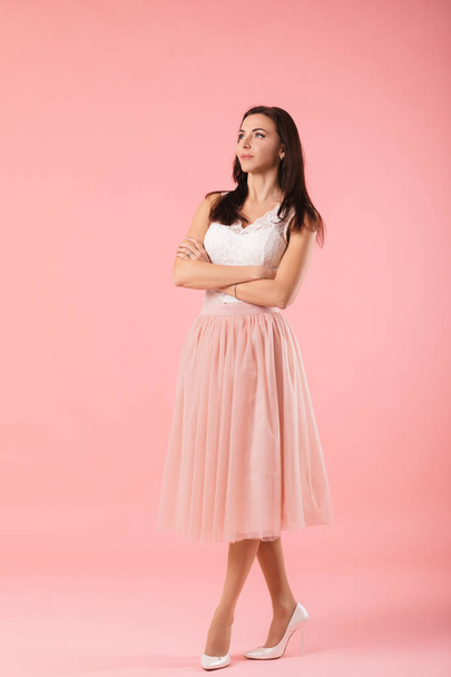 charming woman in pink lush skirt on pink background. - Photo, image
