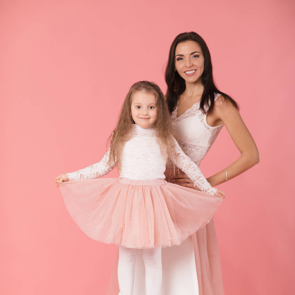 charming mother and smiling daughter on pink background - Фото, зображення