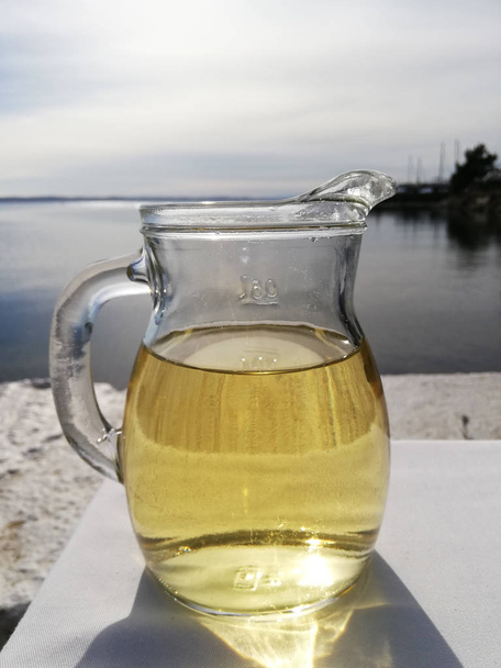 Jag met witte wijn op tafel met uitzicht op zee en jacht - Foto, afbeelding