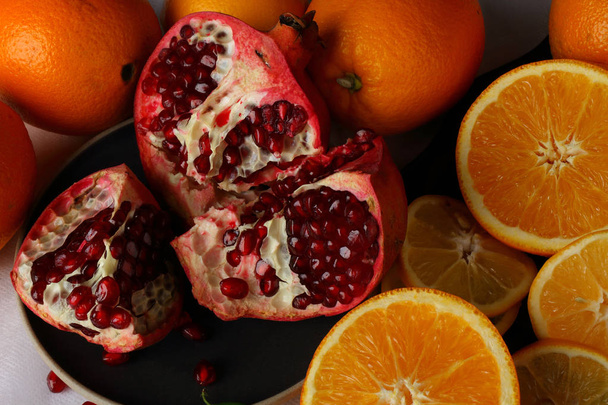 Still life with open pomegranate, oranges and lemon wedges - Foto, Bild