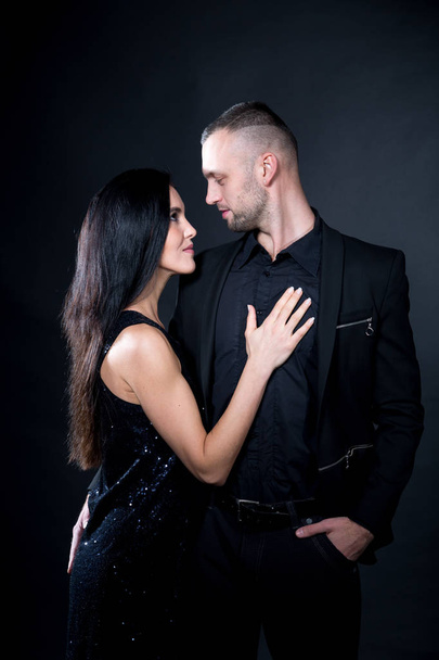 Lovers man and woman role-playing game. Dominate obey undress seduce a partner. Business suit formal style. Girl dressed black dress, man holds hand on her hip. Sensual date idea. Thematic bdsm party - Zdjęcie, obraz