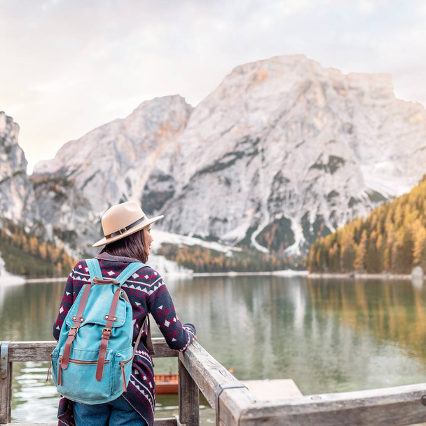 Asian woman traveler on the shore of the famous tourist lake Braies in the Dolomites Alps, Italy. The concept of travel and adventure in the mountains at autumn season - Photo, Image