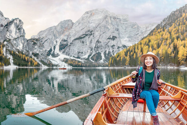 Gelukkig Aziatische vrouw zitten in de houten vintage boot drijvend en zeilen op een Prags meer in de Italiaanse Alpen bergen, reizen en droom vakantie concept - Foto, afbeelding