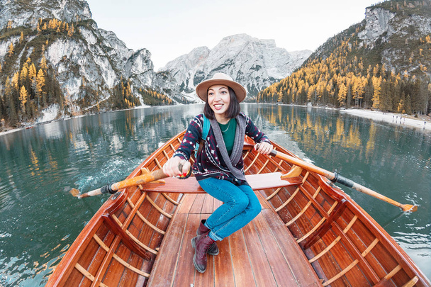 Gelukkig Aziatische vrouw zitten in de houten vintage boot drijvend en zeilen op een Prags meer in de Italiaanse Alpen bergen, reizen en droom vakantie concept - Foto, afbeelding