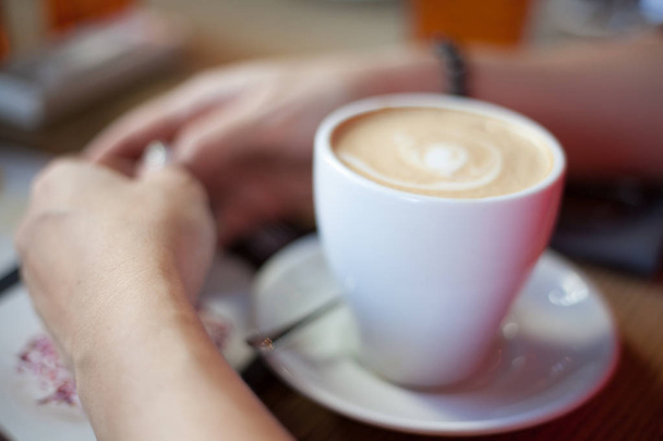 Blurred background with white cup of cofee and woman hands. - Photo, Image