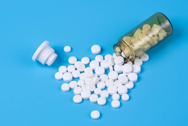 Geassorteerde farmaceutische geneeskunde pillen, witte pillen in de glazen fles op een oranje achtergrond. Ruimte voor tekst kopiëren - Foto, afbeelding