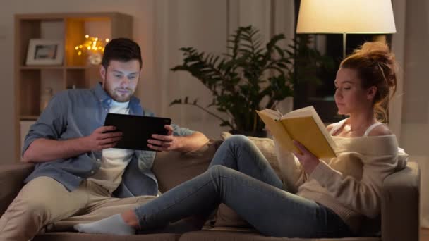 couple with tablet computer and book at home - Filmati, video