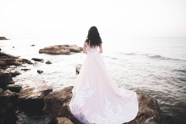 Senhora bonita, noiva posando em um vestido de noiva perto do mar no pôr do sol - Foto, Imagem