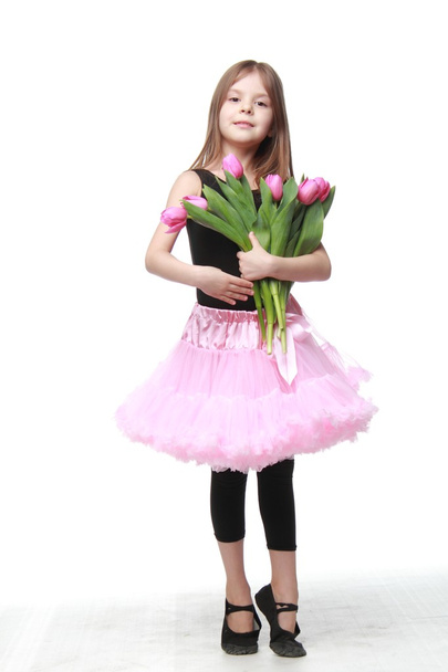 Cute little dancer with long hair holding a beautiful bouquet of tulips - Valokuva, kuva