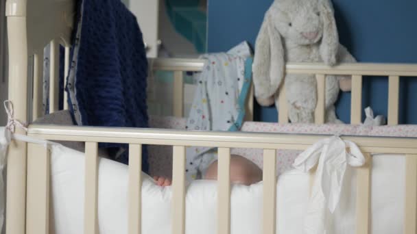 Toddler stands up in crib, looks out from pillow and happily smiles - Video