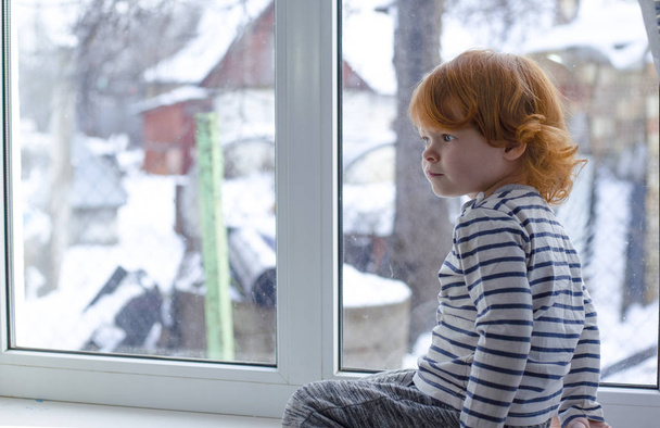 μικρό κορίτσι με τα κόκκινα μαλλιά από το παράθυρο, redheaded κοριτσάκι - Φωτογραφία, εικόνα