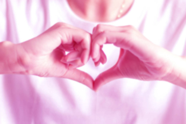Rozmyte różowy odcień obrazu osoby dołączyć dwie ręce, aby być serce do gest miłości; ręka oznaki miłości. - Zdjęcie, obraz