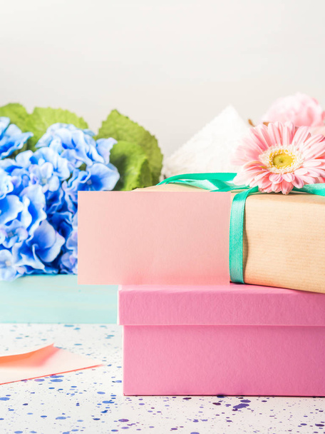 leere rosa Karte und gestapelte Geschenkboxen. Blumen - Foto, Bild