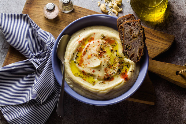 mashed cauliflower with cashew nuts in plates on the table with rye bread . healthy winter cooking, vegan recipe for the whole family or dinner with friends - Photo, image