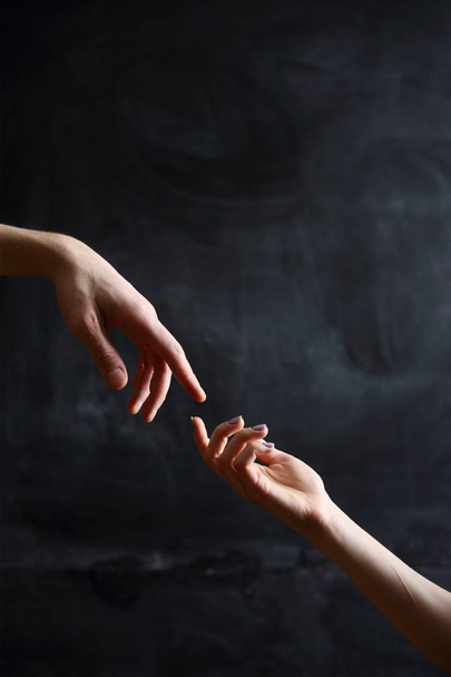 hands of people in symbol of relationships, black background - Photo, Image