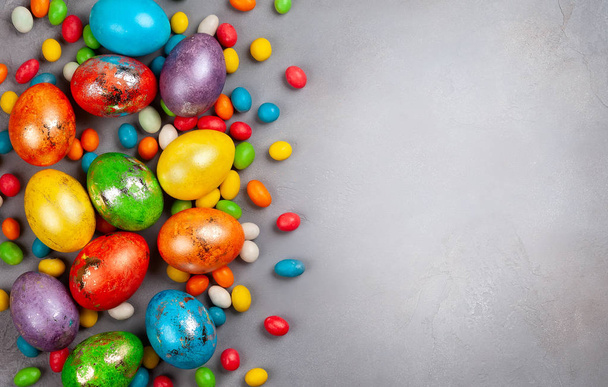 Coloridos huevos de Pascua y dulces de Pascua de chocolate sobre fondo gris. Vista superior con espacio de copia. Concepto festivo de Pascua
. - Foto, imagen
