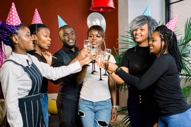 Portrait of happy young African friends touching the glasses with each other and celebrating birthday - Photo, image