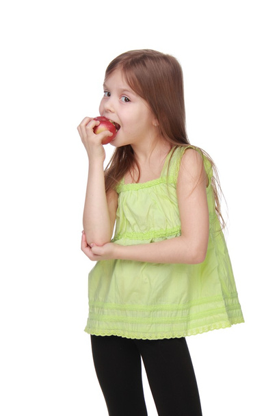 Portrait of a beautiful little girl eating an apple - Фото, изображение