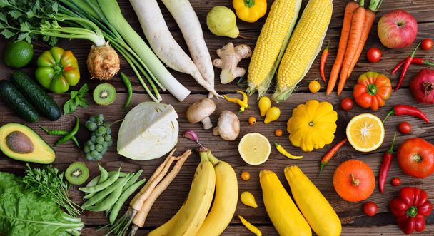 Frutas y verduras blancas, verdes, amarillas, naranjas, rojas sobre fondo de madera. Comida saludable. Alimentos crudos multicolores
 - Foto, Imagen