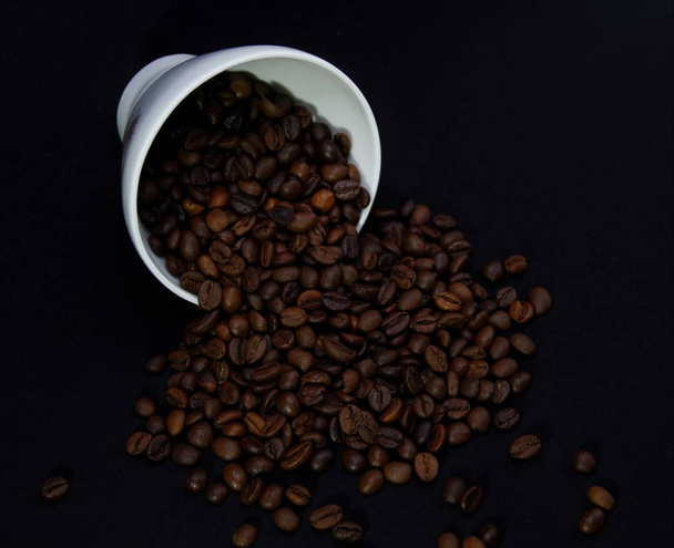 コーヒー豆と黒の背景の上にカップ - 写真・画像