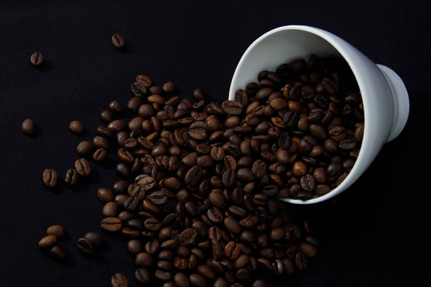 κόκκους καφέ και κύπελλο σε μαύρο φόντο - Φωτογραφία, εικόνα