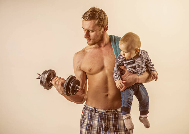 Keeping fit. Father and child training together. Healthy family lifestyle. Strong man with dumbbells hold baby boy. Father build biceps triceps with son. Active family enjoy sport and fitness - Valokuva, kuva