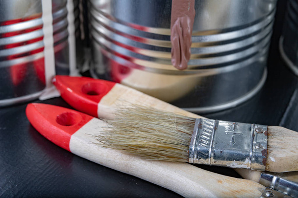 Brushes for painting with paint and cans on a workshop table. Painting accessories prepared for painting. Dark background. - Foto, immagini