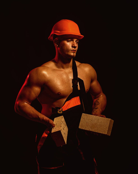 We are building dreams. Bricklayer worker. Construction worker or builder at work at building site. Man worker hold bricks in muscular hands. Muscular man does masonry work - Foto, Imagen
