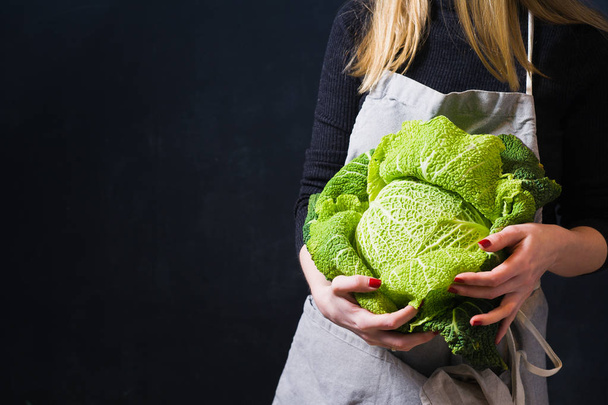 The farmer is holding a Savoy cabbage. Dark background, side view, space for text - 写真・画像