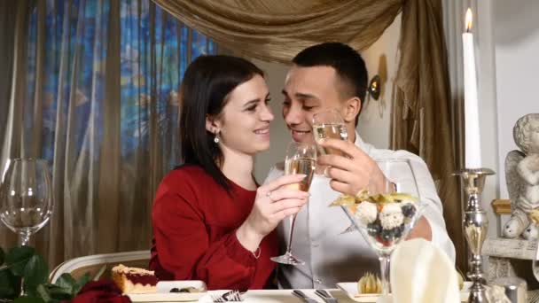 Fiatal pár pirítás pezsgő az étterem. Társkereső. Fiatal férfi és a nő romantikus vacsora, ivás étteremben, Valentin-nap ünneplése. Romantikus fogalma és szerelmi. HD - Felvétel, videó