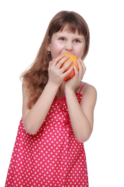 Little girl in bright dress holding a grapefruit - 写真・画像