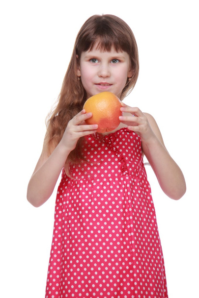 Little girl in bright dress holding a grapefruit - Фото, изображение