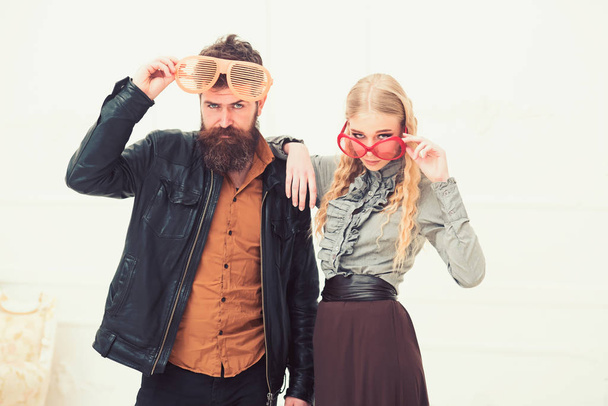 Stylish couple in huge orange glasses posing in studio. Man with nice beard and mustache hugging blond attractive girl. Fashion shooting - Fotoğraf, Görsel