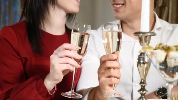 恋人の日にレストランでグラスをチャリンという音します。クローズ アップ。2 月 14 日を祝うロマンチックなディナー レストランで飲む女性、若い男。ロマンチックな概念や恋愛。hd - 映像、動画